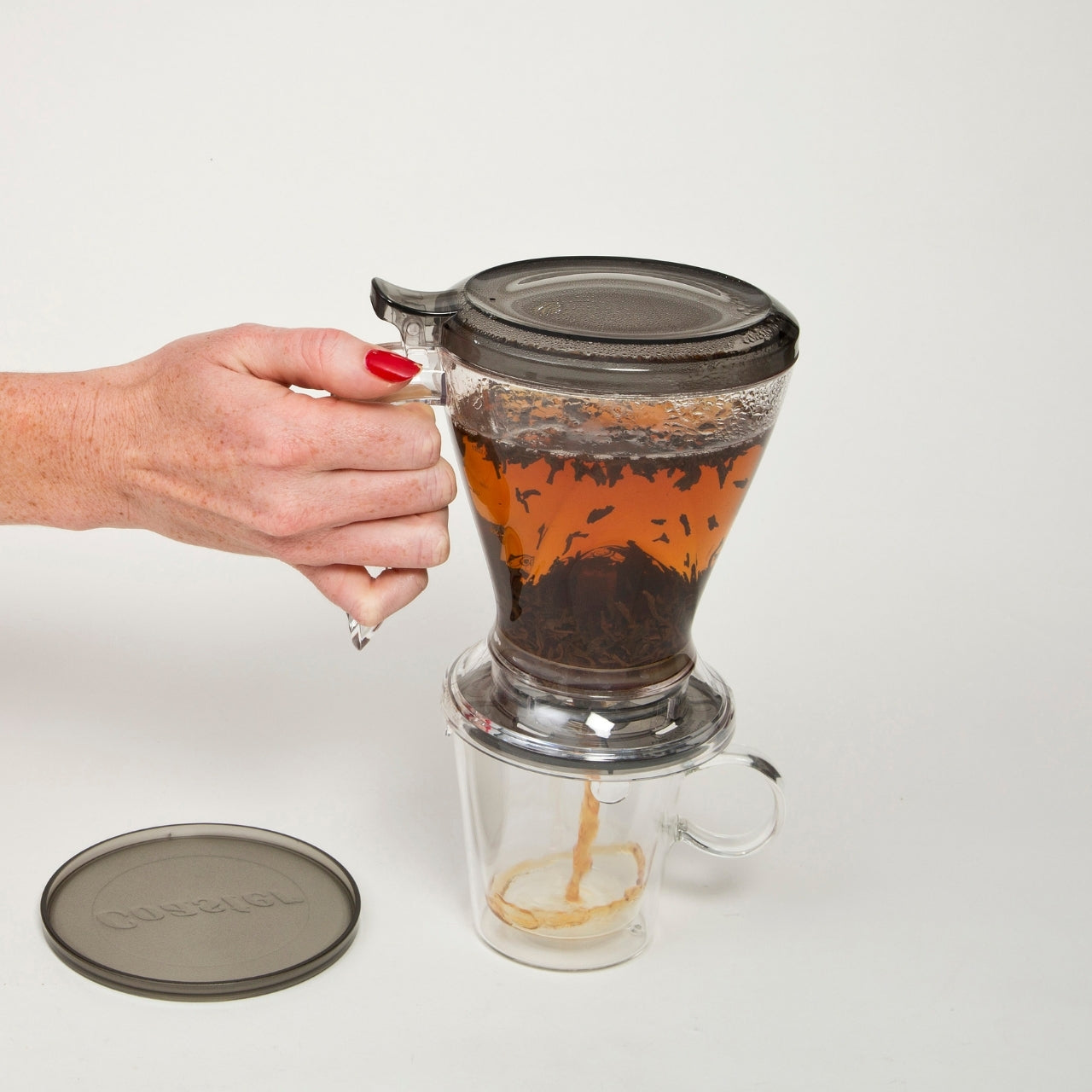 A person filtering the tea from the Magic Gravity Infuser For Tea & Coffee